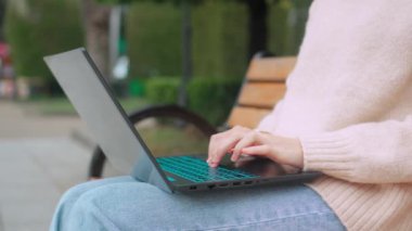 Parkta dizüstü bilgisayarda yazı yazan kadınların yakın çekimleri. Çimenlerde oturuyor, uzaktan çalışıyor. Bilgisayar kullanan tanınmayan bir kadın. Laptop, Hacker ya da serbest bilgisayar üzerinde çalışıyor..