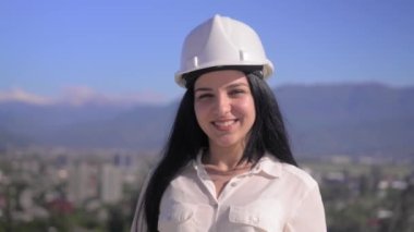 İnşaat alanında çalışırken kask takan orta yaşlı kadın mimar kameraya gülümsüyor. Başarılı ve gururlu müfettiş. Kadın Mühendis Portresi. İnşaat Yöneticisi