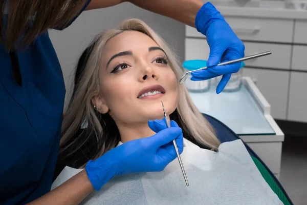 Stomatologist checkup. Close-up of a young woman with her mouth open, a dentist with the help of dental equipment makes an examination of the oral cavity