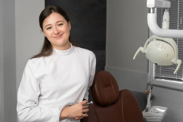 Joven Dentista Sonriente Traje Blanco Para Cerca Silla Dental Mira —  Fotos de Stock