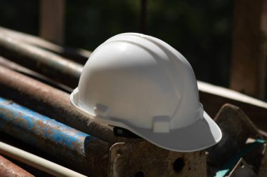 İnşaat alanındaki metal yapıların üzerinde duran beyaz bir miğferin yakın çekimi, güvenlik önlemleri....