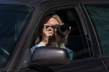 Gizli fotoğrafçılık. Paparazzi Concep Fotoğrafçısı profesyonel kamerasını kullanıyor. Araba vitrinindeki fotoğrafçı kız. Mobil muhabir. İş yerinde foto muhabiri. Dedektif ya da dedektif..