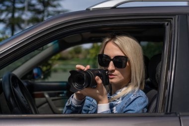 Gizli fotoğrafçılık. Paparazzi Concep Fotoğrafçısı profesyonel kamerasını kullanıyor. Araba vitrinindeki fotoğrafçı kız. Mobil muhabir. İş yerinde foto muhabiri. Dedektif ya da dedektif..
