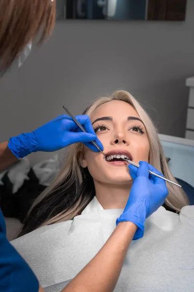 Dentysta Bada Zęby Młodej Pacjentki Nowoczesnym Gabinecie Dentystycznym Zdjęcie Pionowe — Zdjęcie stockowe
