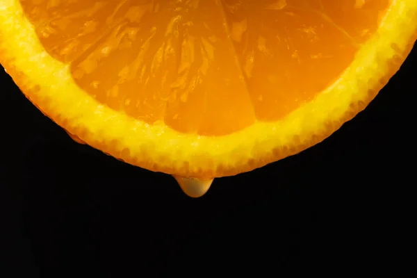 黒い背景にオレンジ色のスライスから落ちるジュースの一滴のマクロ写真 フルーツの背景 — ストック写真