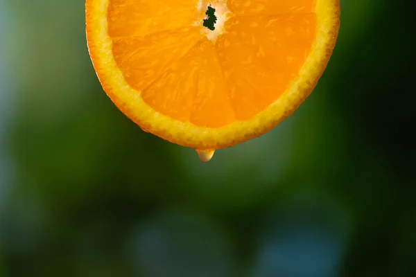 Gota Jugo Goteando Una Rebanada Naranja Sobre Fondo Verde Borroso — Foto de Stock