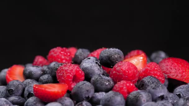覆盆子和草莓在它们的轴上旋转着 黑色背景上的多汁浆果 有文字的空间 混合着新鲜的夏天浆果的芬芳 红黑健康 — 图库视频影像