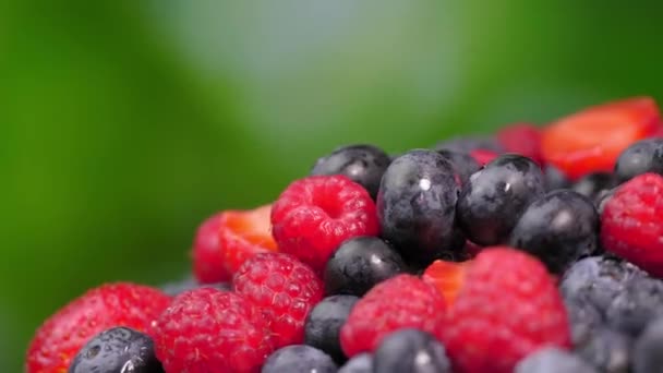 覆盆子和草莓在它们的轴上旋转着 多汁的浆果 绿色背景 有文字空间 混合着新鲜的夏天浆果的芬芳 红黑健康 — 图库视频影像