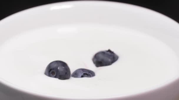 覆盆子 蓝莓掉在牛奶里 溅满了脏水 尽收眼底 新鲜的红草莓掉在碗里的牛奶里 做奶昔 酸奶或冰沙 健康饮食的概念 — 图库视频影像