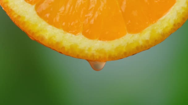 从成熟的橙子片上滴下的果汁或水 新鲜蔬菜和水果的概念 清澈的汁液滴在绿色的背景上 慢动作 — 图库视频影像