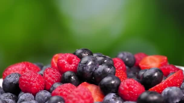 覆盆子和草莓在它们的轴上旋转着 多汁的浆果 绿色背景 有文字空间 混合着新鲜的夏天浆果的芬芳 红黑健康 — 图库视频影像