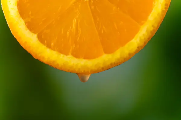 Csepp Narancslé Csöpög Egy Szelet Narancsból Elmosódott Zöld Háttérrel Makro — Stock Fotó