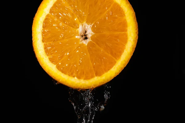 黒い背景に流れる水でオレンジ色のジューシーなスライスのクローズアップ マクロ写真 フルーティーシトラスの背景 — ストック写真