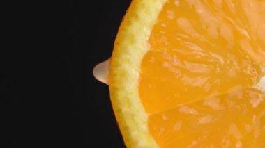 Olgun portakaldan bir damla meyve suyu ya da yakın plan su damlası. Taze sebze ve meyve kavramı. Yeşil arka planda berrak meyve suyu damlayan turuncu. Ağır çekim. dikey video