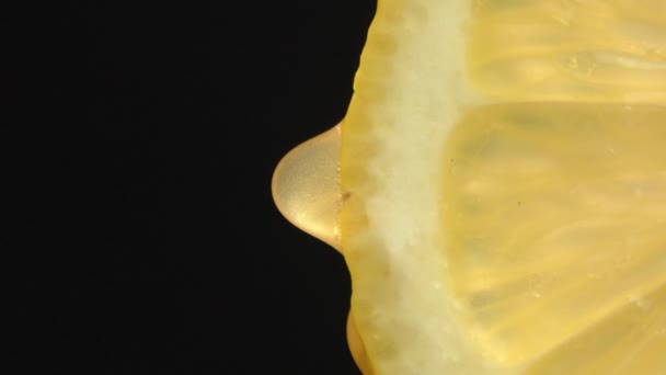 熟したレモンのスライスからジュースや水の滴を閉じます 新鮮な野菜や果物のコンセプト 緑色の背景にマクロドリッピングクリアジュースを含むレモン スローモーション バーティカルビデオ — ストック動画
