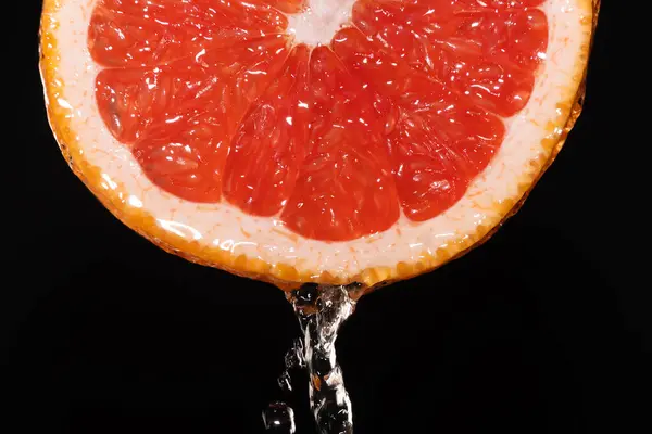 Bir dilim greyfurtun makro fotoğrafçılığı ve bir jet su, sıçramalar. Greyfurt arkaplanı, doku
