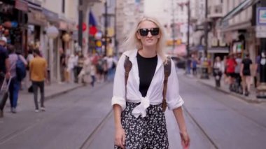 İstanbul 'da Türk caddesinde, üzerinde tramvayların, rayların olduğu yolda yürüyen beyaz tişörtlü, güzel bir kadın kalabalık ve gezgin şehir insanlarına karşı. Istiklai.