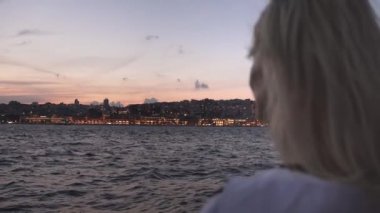 İstanbul 'da feribotta bulanık, güzel sarışın, boğazda dinleniyor. Gemiye binen beyaz tişörtlü bir kız. Tekne. Dalgalar arka planda. Tekneyle şehri gezmek..
