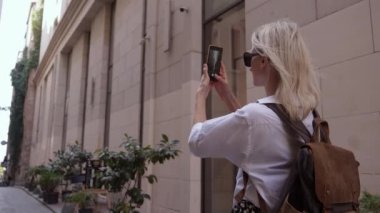 Mutlu sarışın turist kız cep telefonu kamerasıyla eski şehir caddesini çekiyor, kadın gezgin Avrupa 'nın Narrow caddesindeki yaz gezisinde şehir fotoğraflarını çekiyor. İnce kadın.