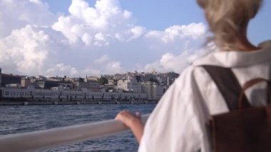 İstanbul 'da feribotta, Bosphorus' ta tatil yapan güzel sarışın iş kadınının arkası. Gemiye binen beyaz tişörtlü bir kız. Tekne. Dalgalar arka planda. Tekneyle şehri gezmek.