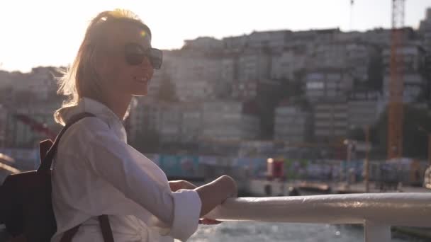 イスタンブールのフェリーでサングラスで若い美しい実業家ブロンドの女性ボスポラスに飛ぶ 白いスタイリッシュなシャツに乗る船の女の子 ボート旅行 背景にある波 市内のボートで観光 — ストック動画