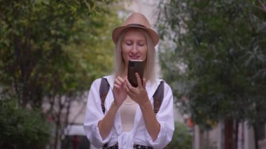 Salon şapkalı kadın turist ve ryuukzakom akıllı telefondan uygulama eğitimi alıyor. Şehir haritası, taksi, otel. Kalacak yer, uygulama konsepti ya da seyahat yazılımı bulmak. Neşeli Turist