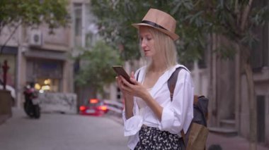 Salon şapkalı kadın turist ve ryuukzakom akıllı telefondan uygulama eğitimi alıyor. Şehir haritası, taksi, otel. Kalacak yer, uygulama konsepti ya da seyahat yazılımı bulmak. Neşeli Turist