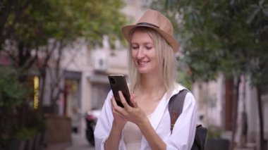 Salon şapkalı kadın turist ve ryuukzakom akıllı telefondan uygulama eğitimi alıyor. Şehir haritası, taksi, otel. Kalacak yer, uygulama konsepti ya da seyahat yazılımı bulmak. Neşeli Turist
