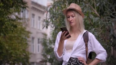 Salon şapkalı kadın turist ve ryuukzakom akıllı telefondan uygulama eğitimi alıyor. Şehir haritası, taksi, otel. Kalacak yer, uygulama konsepti ya da seyahat yazılımı bulmak. Neşeli Turist