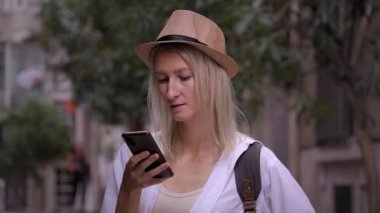 Salon şapkalı kadın turist ve ryuukzakom akıllı telefondan uygulama eğitimi alıyor. Şehir haritası, taksi, otel. Kalacak yer, uygulama konsepti ya da seyahat yazılımı bulmak. Neşeli Turist