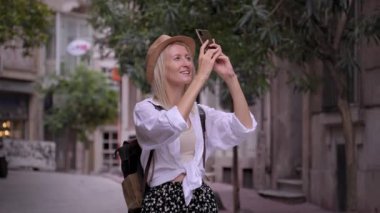 Mutlu sarışın turist kız cep telefonu kamerasıyla eski şehir caddesini çekiyor, kadın gezgin Avrupa 'nın Narrow caddesindeki yaz gezisinde şehir fotoğraflarını çekiyor. İnce kadın.