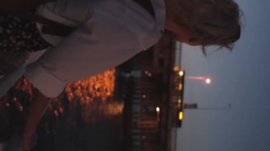 Akşamları güzel sarışın bir kadın İstanbul feribotunda, boğazını dinlendirirken. Gemide beyaz tişörtlü bir kız var. Dalgalar ve arka planda şehir ışıkları. Şehirde gezinti teknesi