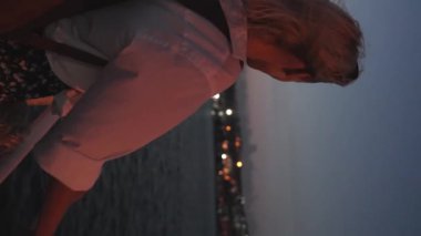 Akşamları güzel sarışın bir kadın İstanbul feribotunda, boğazını dinlendirirken. Gemide beyaz tişörtlü bir kız var. Dalgalar ve arka planda şehir ışıkları. Şehirde gezinti teknesi