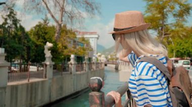 Sırt çantalı, hasır şapkalı ve güneş gözlüklü kadın turist Venedik kanalı manzarasının keyfini çıkarıyor ve turizm, tatil veya seyahat kavramını geliştiriyor.