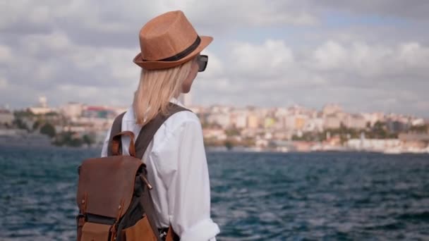 年轻美丽的女人 背着太阳镜 沿着伊斯坦布尔的长廊走着 看着船在博斯普鲁斯海峡上航行 微笑着看到了旅游姑娘的画像 探索城市和旅行 — 图库视频影像