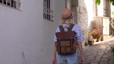 Türkiye ya da Yunanistan 'ın eski kenti caddesinde sırt çantalı genç ve narin bayan turistin arka manzarası. Seyahat konsepti atmosferik destansı güzel an.