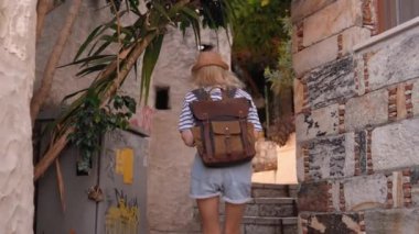 Türkiye ya da Yunanistan 'ın eski kenti caddesinde sırt çantalı genç ve narin bayan turistin arka manzarası. Seyahat konsepti atmosferik destansı güzel an.