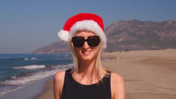 ภาพระยะใกล ของหญ งสาวในหมวกซานตาคลอสในว นคร มาสหร ใหม บนชายหาดบนพ นหล งของภ เขาในแว — วีดีโอสต็อก