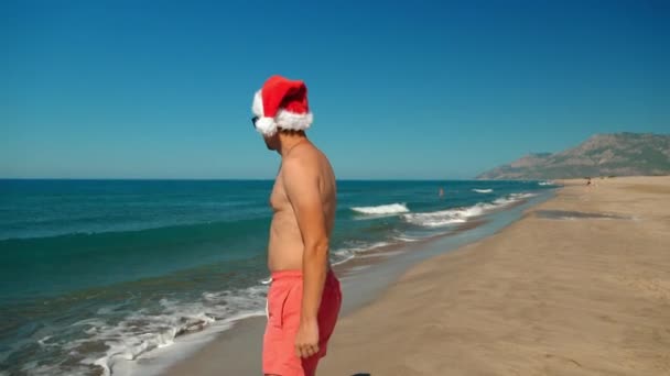 Noel Noel Baba Şapkalı Adam Plajda Sahilde Güneş Gözlüklü Dağların — Stok video
