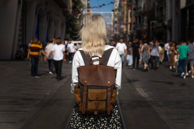 Güneşli bir günde İstanbul 'un popüler Istiklal caddesinin ortasında sırt çantalı, beyaz gömlekli, etekli, şık bir bayan turist duruyor. Seyahat kavramı