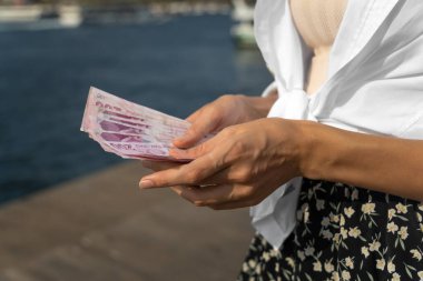 Güneşli bir günde sokakta 200 lira Türk parası sayan kadınların yakın çekimi. Türkiye Cumhuriyeti Merkez Bankası.