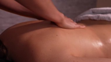 Profesyonel masör, rahatlama, güzellik ve vücut bakımı kavramı. Ev masajı. Güzeller güzeli bir kadın spa salonundaki profesyonel sağlık masajından zevk alıyor. Sırtına masaj yapan kadın terapistin yakın çekimi.