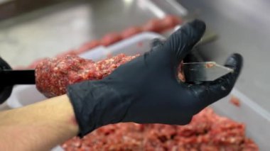 Şef şişe zorla et yapıştırıyor ve onu ticari mutfakta ızgarada lula kebap pişirmek için yapıyor. Siyah eldivenli yakın çekim elleri.
