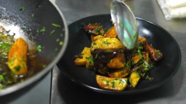 Kızarmış patates. Manzarası harika, şef restoranda, fırında patates dilimlerini siyah tabakta kızartma tavasına koyuyor. Altın kabuklar ışıkta parıldıyor. Patates hazırlığı..