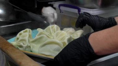 Lokantadaki mutfakta kaynar su ve buharla pişirilmiş khinkali ile büyük kaşık yakın çekim. Aşçı khinkali 'yi kabından çıkarıp tabağa koyar..