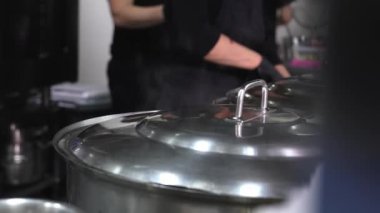 Yemek ya da çorba tencerelerde pişirilir, su ve buhar restoranın mutfağında buharlaşır. Bulanık arkaplan, seçici odaklanma. Tencereler buharlanıyor.