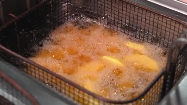 土豆片的特写是在一个很深的法国里烹调的 土豆在厨房的一个深沟里用油油炸 — 图库视频影像