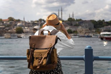 Sırt çantalı güzel bir turist kadın, İstanbul 'daki Galata Köprüsü' nde dürbünle bakıyor. Turizm ve seyahat kavramı