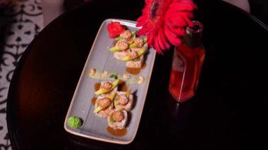 Sıcak bir restoranın içinde çiçekli avokado ve karidesli sushi yakın plan.
