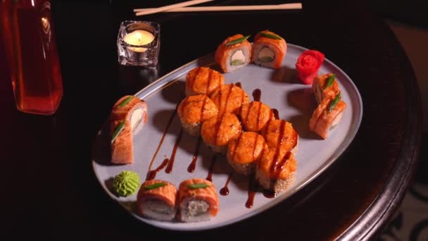 居心地の良い雰囲気のキャンドルとレストランのテーブルに美味しい焼き寿司ロールのクローズアップ 公共ケータリングの概念 — ストック動画